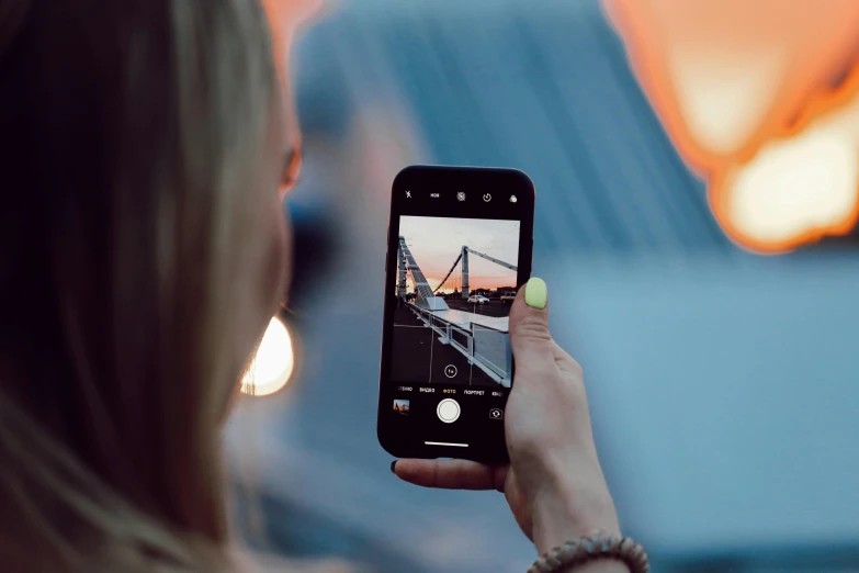 a woman takes a selfie of the camera with her cell phone