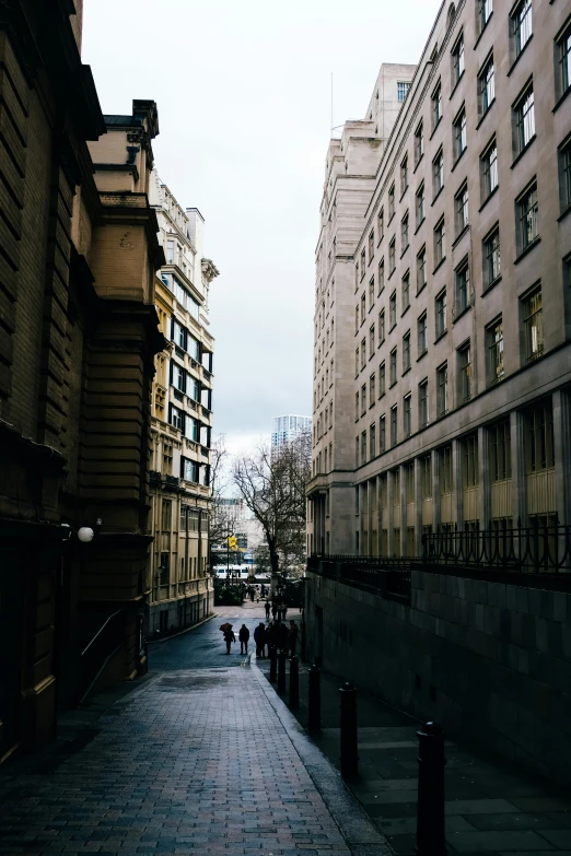 people are walking down a city street while buildings line the sides