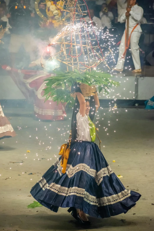 a woman in a blue dress carrying a tree on her head