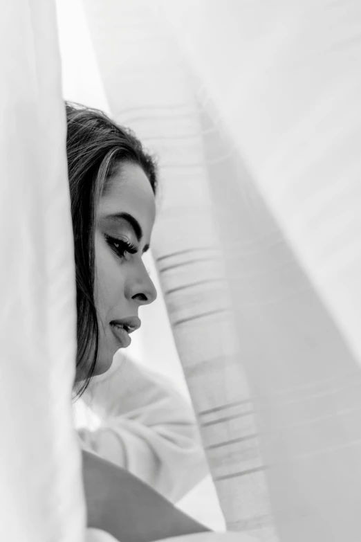 a woman sitting under the curtains looking at soing