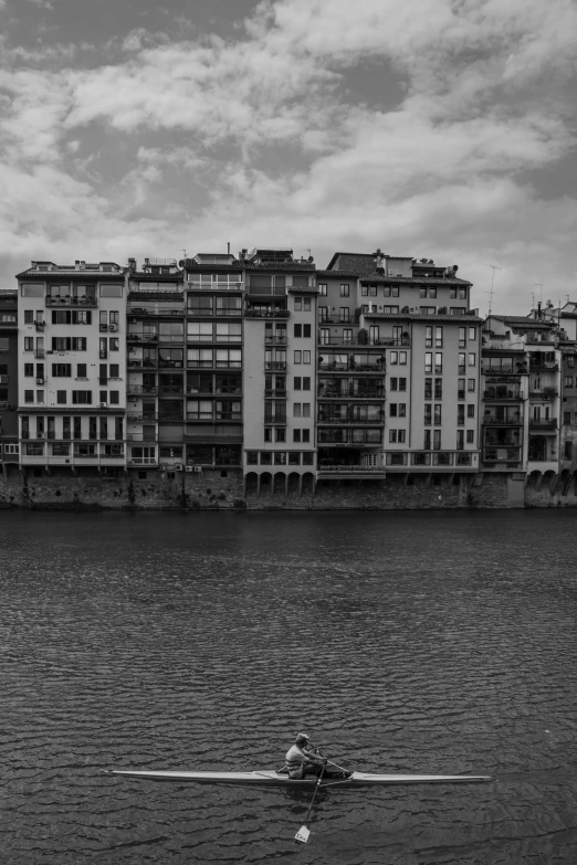 a person rowing in a boat in front of buildings