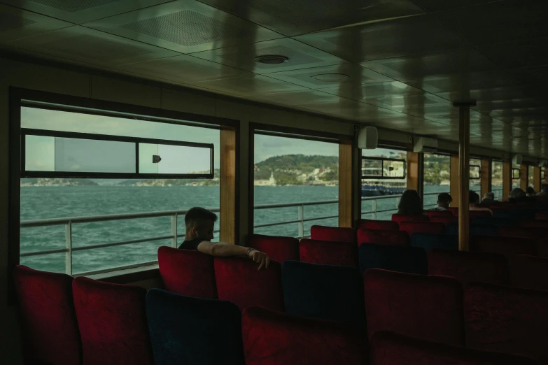 the inside of a train with red seats and ocean view