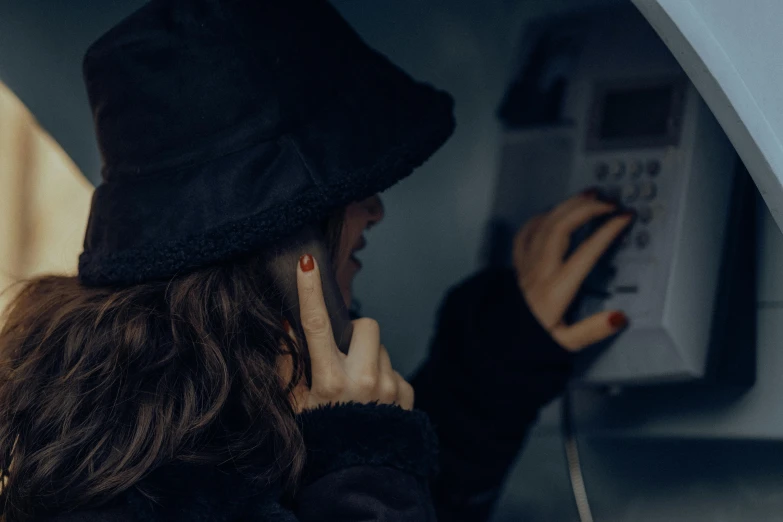 a woman in a hat looking at an object on the wall