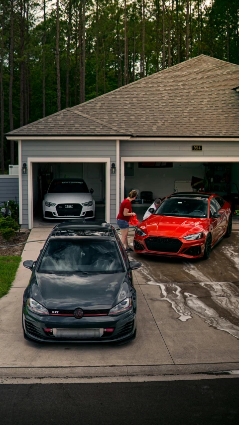 there are cars parked in this driveway with the two men standing beside them