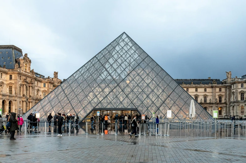 people are standing outside a pyramid shaped building