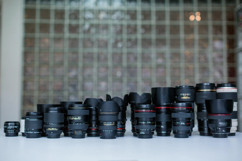 several cameras sitting on a table with the lens hoods up