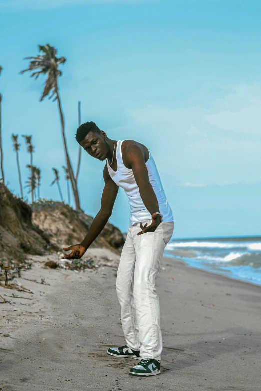 young man in white pants is touching the sand