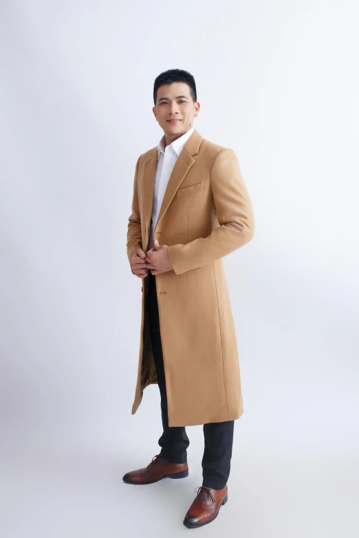 an asian man wearing a long coat, dress pants, and shoes