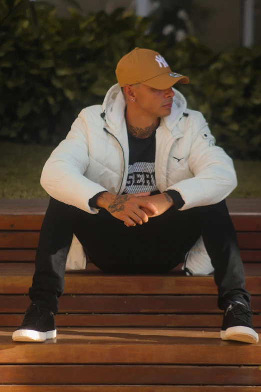 the man in the brown cap sits on a bench with his feet crossed