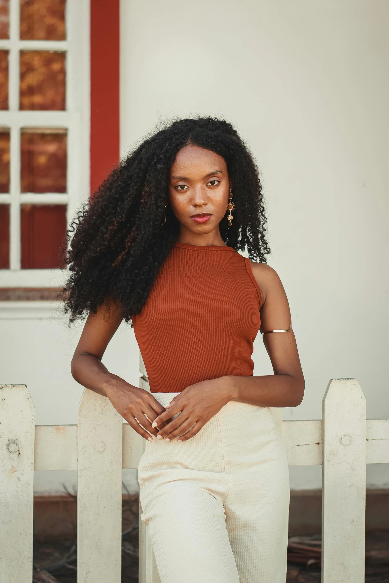 a woman in an orange top sits on a white bench