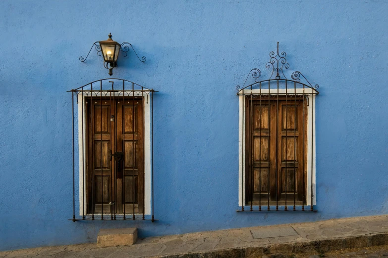 two windows in blue building with iron bars
