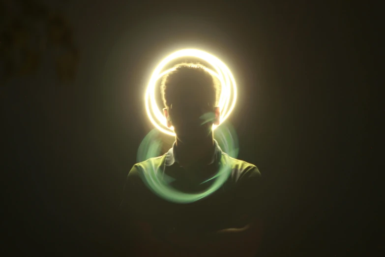 a guy with a green t - shirt in the dark has a glowing circle around him