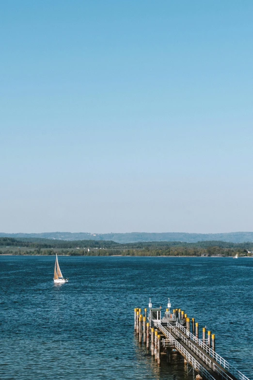 a sail boat sits at the end of a pier