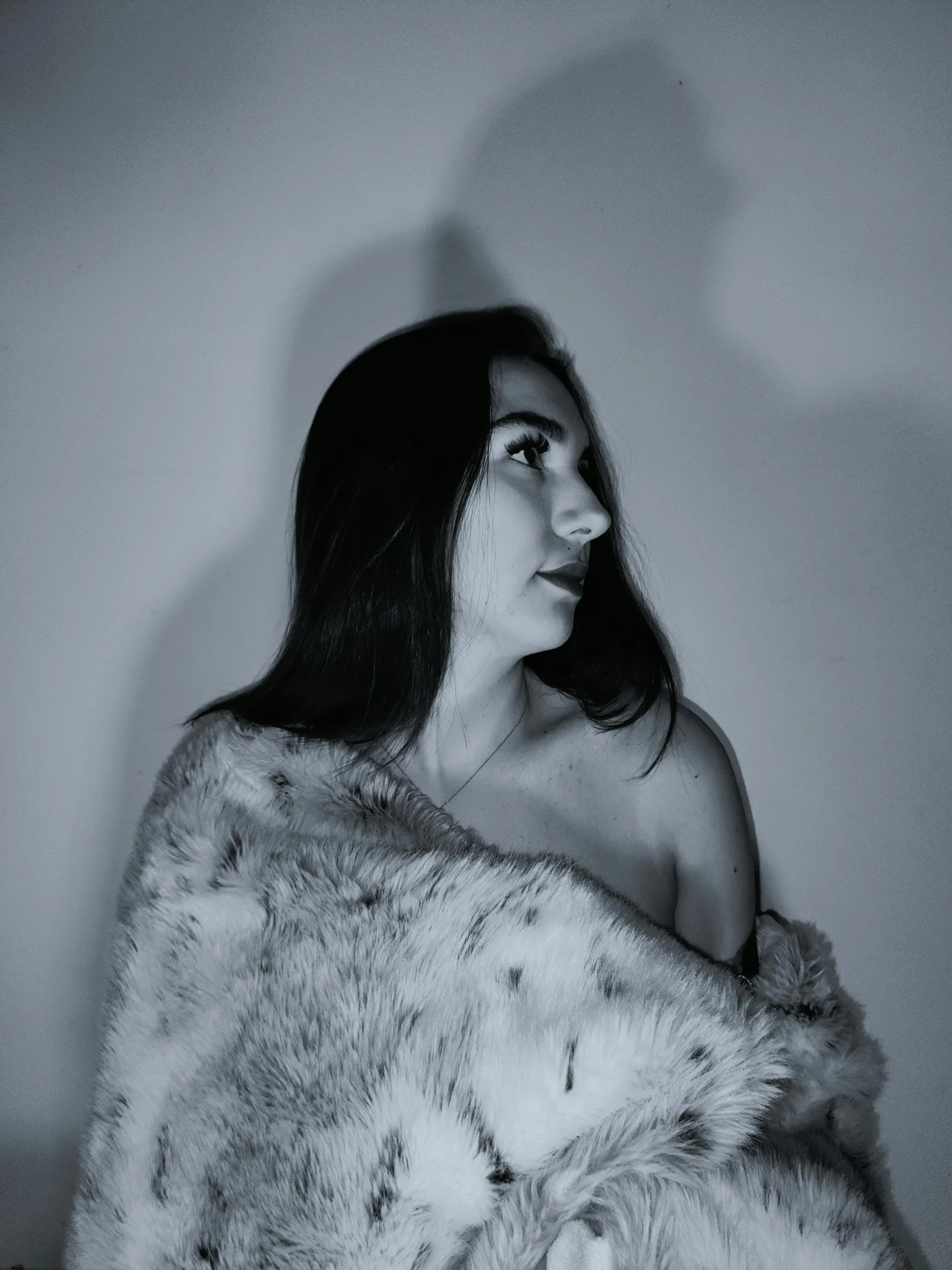 woman with long dark hair wrapped around a fur blanket