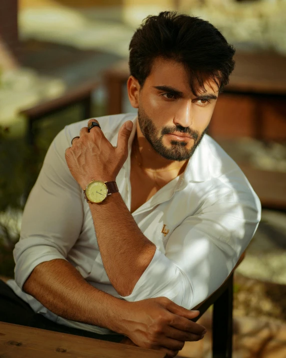 man leaning on a chair, arms folded around wrist, looking up