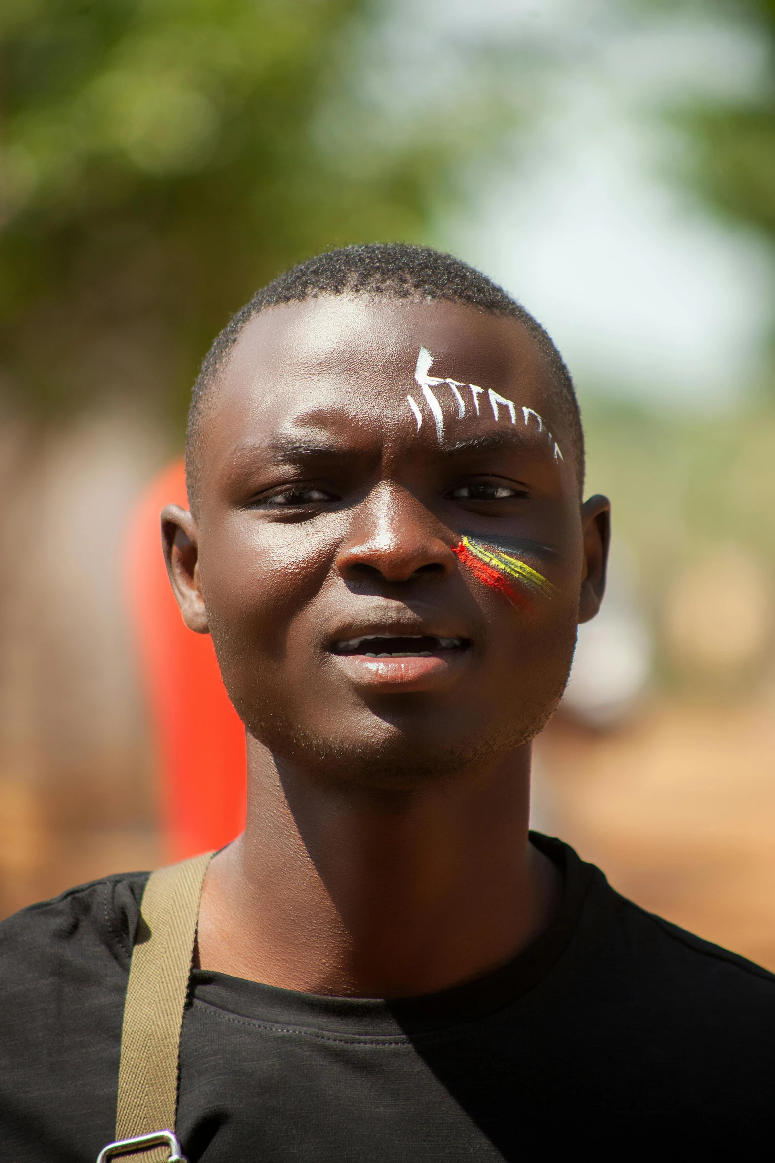 young man with face paint, head band and cross body parts on chest