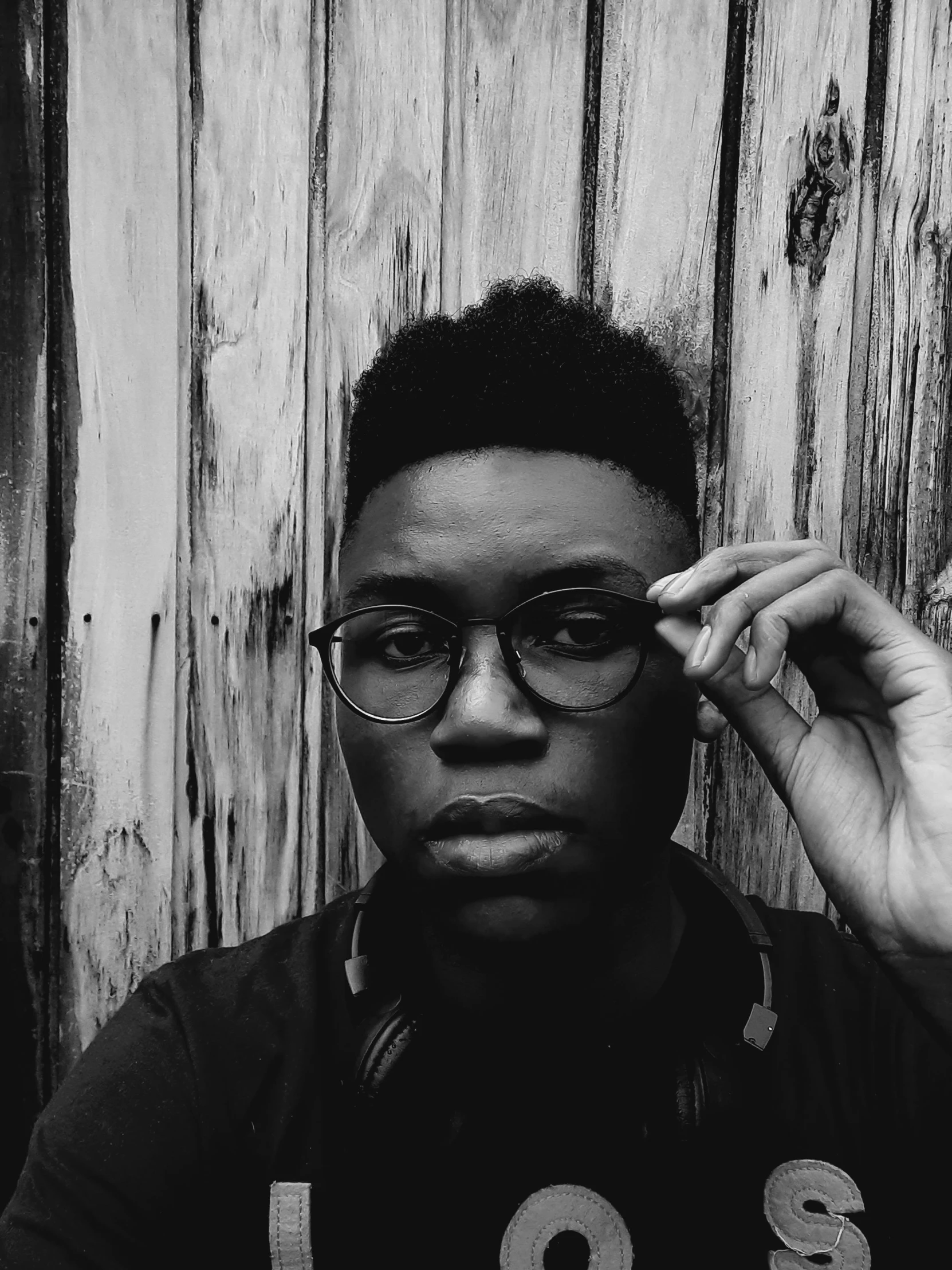 a man in glasses standing in front of a wood wall