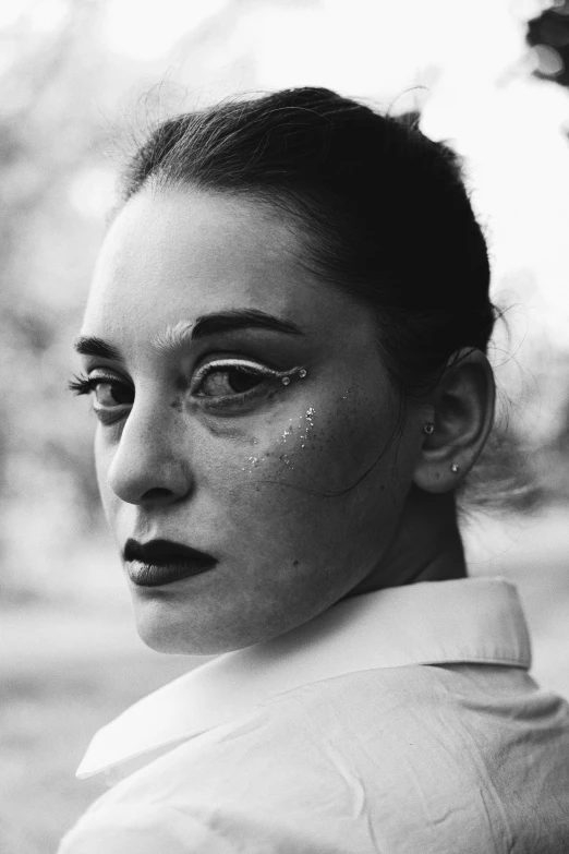 a woman with glittery eyes wearing a jacket and a black tie