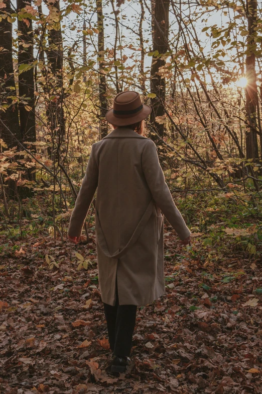 the woman is walking in the woods through the leaves