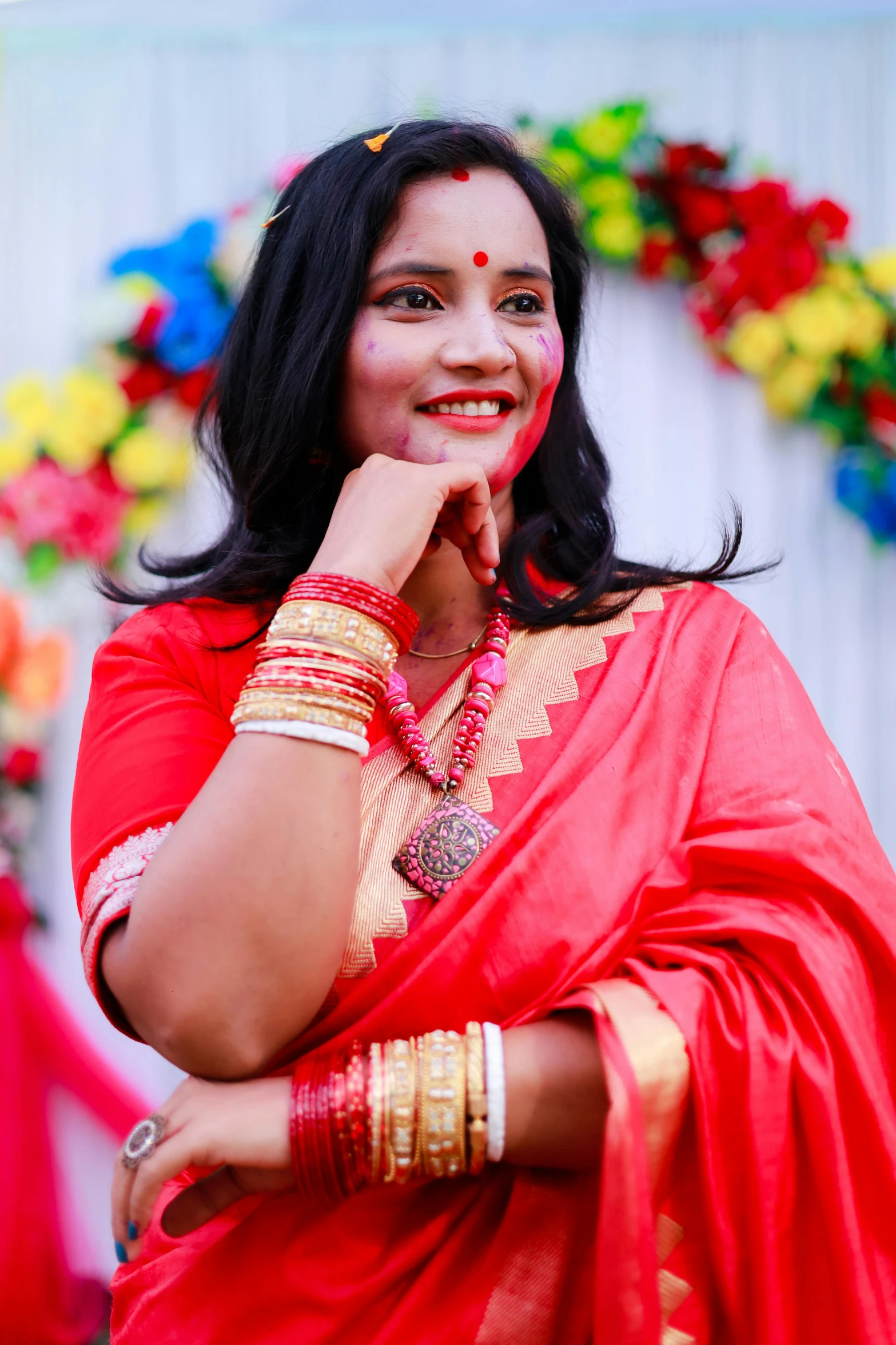 a woman in a red sari, with her hands resting on her chin