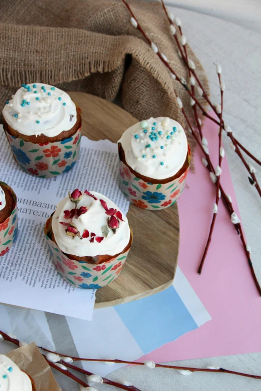 six cupcakes topped with white frosting sitting on top of paper