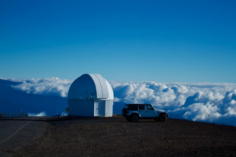 an old white truck parked in front of a telescope