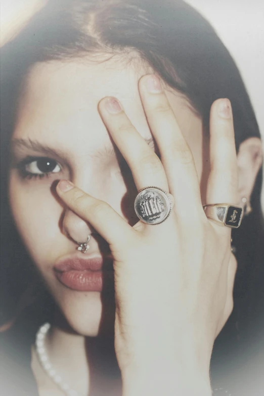 a woman wearing rings is holding her hands to her face