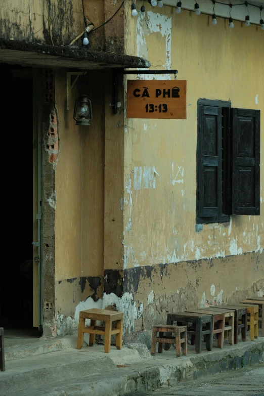 a yellow house with wooden benches outside of it