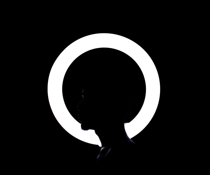 the man's head is silhouetted against the black backdrop