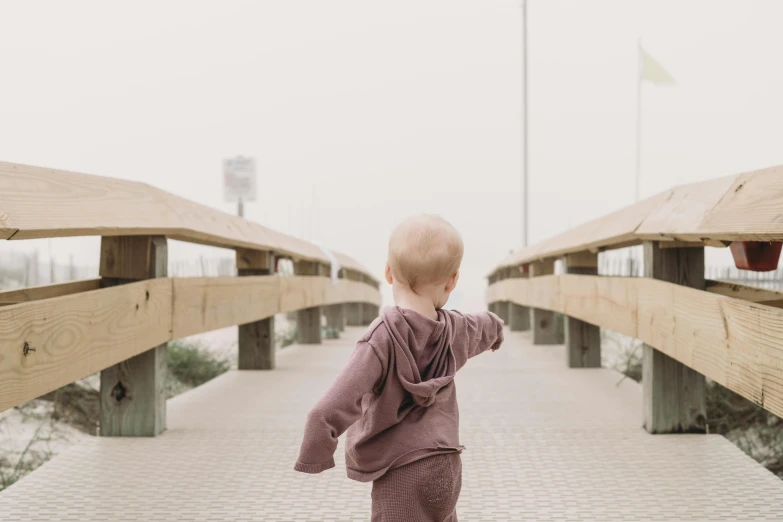 a toddler walking across a bridge holding soing in the air