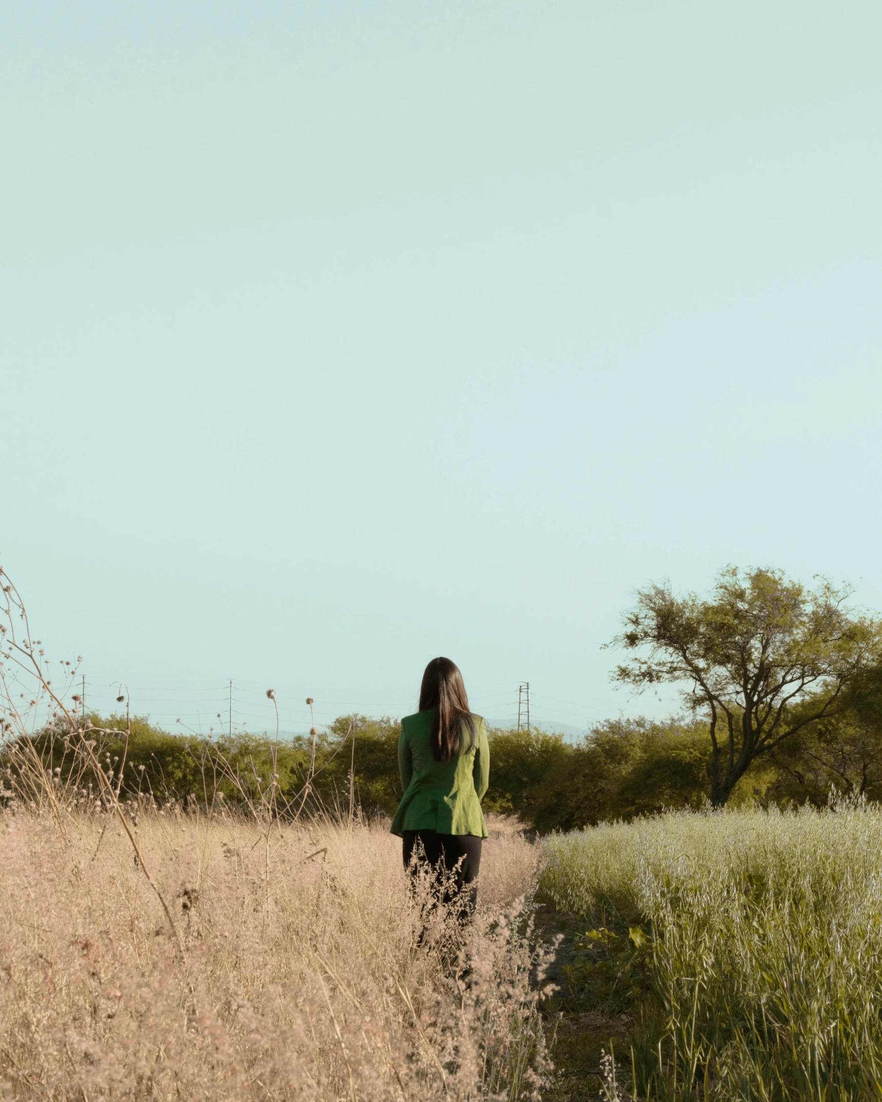 a woman stands in tall grass and smiles