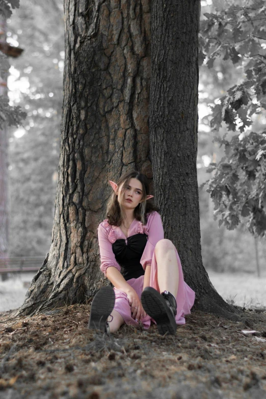 a woman with pigtails is sitting under a tree