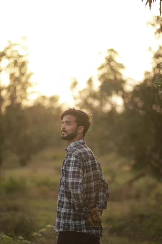 a man stands in an open field with trees in the background