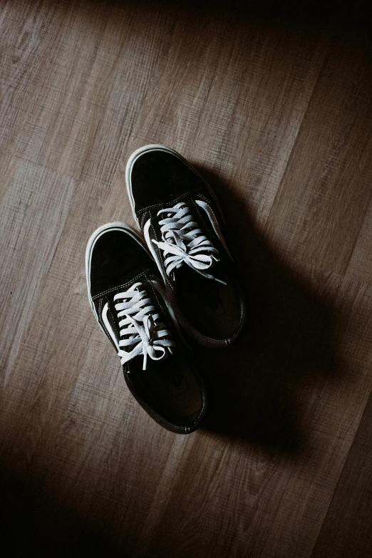 a pair of old black vans that are on a wooden floor