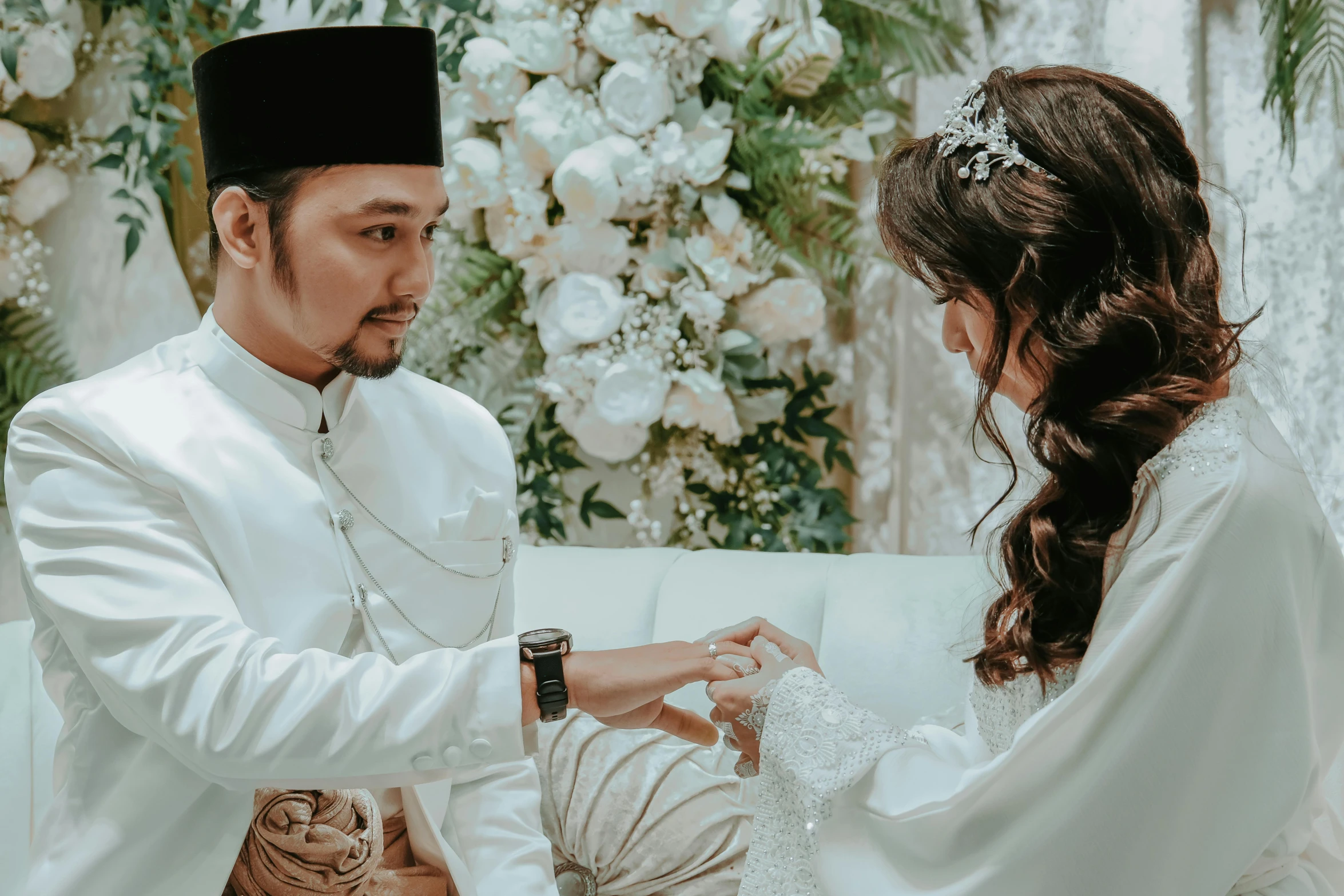 bride and groom in traditional garb doing the finishing touches on her veil