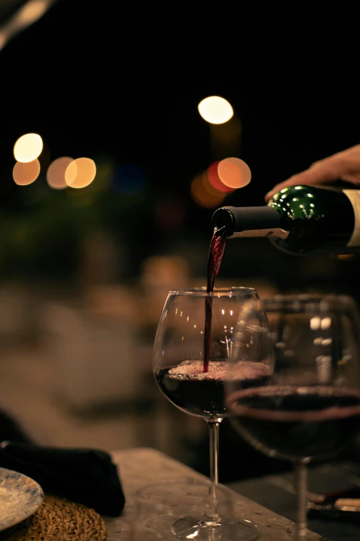 someone is pouring wine into a glass on a bar