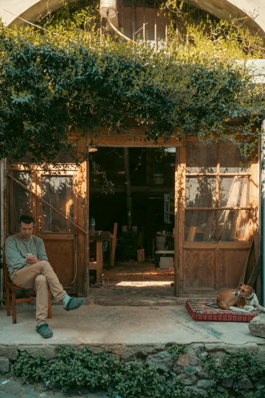 a man sitting in an open door that overlooks a country house with wooden fences and doors