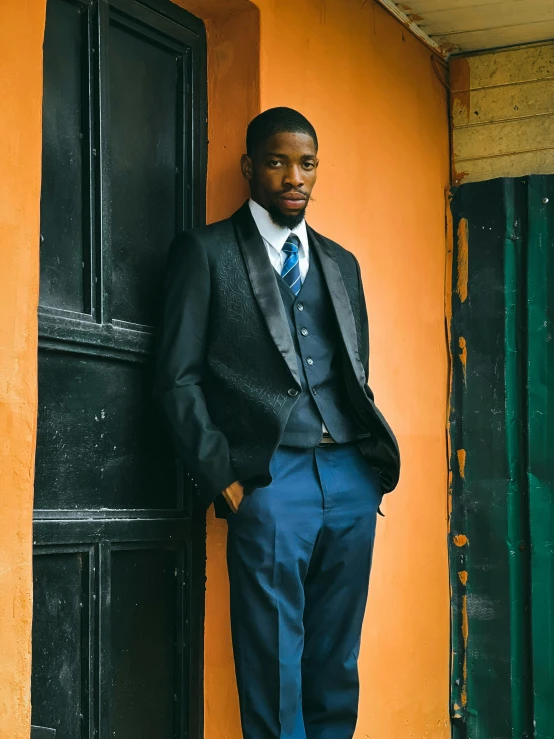 a man leaning on the side of an orange building