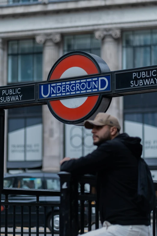 a man sitting outside under ground sign in england