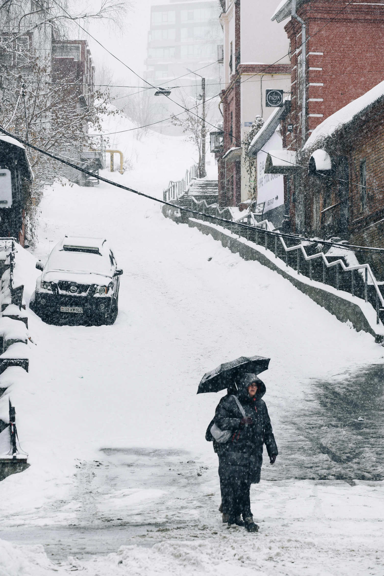 woman walking down snowy street with umbrella in hand