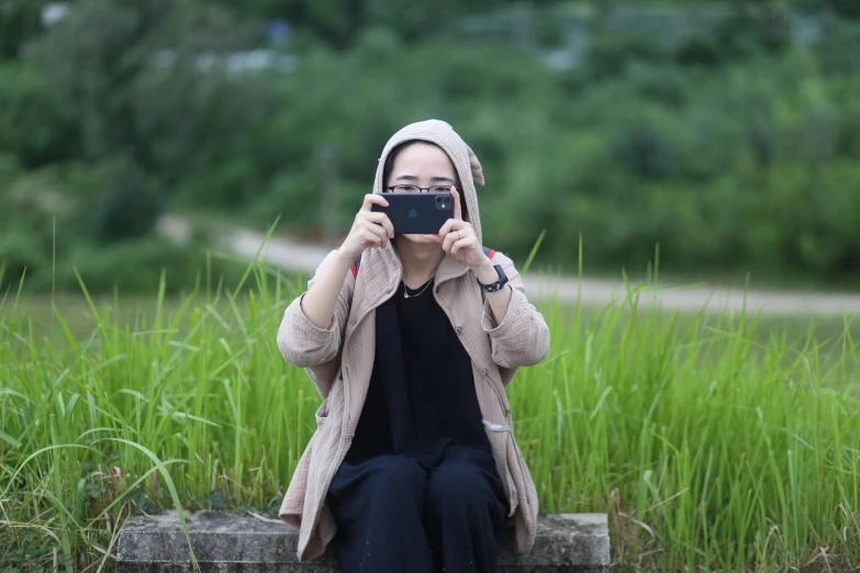 woman taking pograph of grass from top of cement block