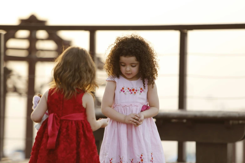 two little girls standing close together near some benches