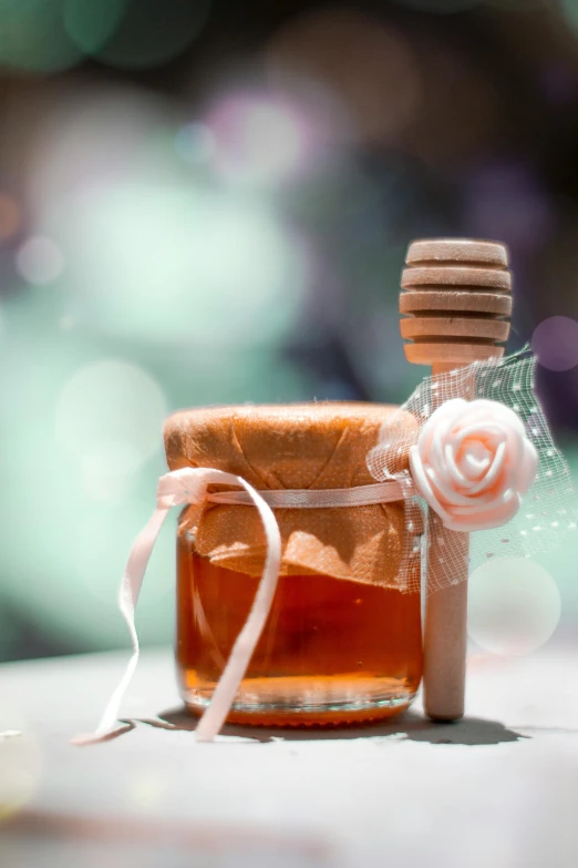 a jar with honey and a small rose flower