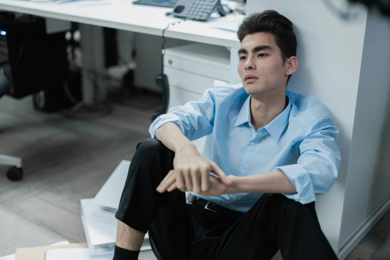 a man sitting in a corner in front of a desk