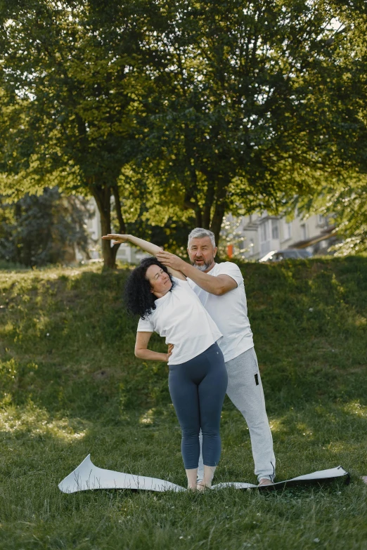 a couple doing yoga on the grass in a park