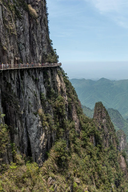 people walking over a suspended walkway in the mountains