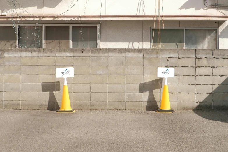 yellow and white street posts and signs next to a brick wall