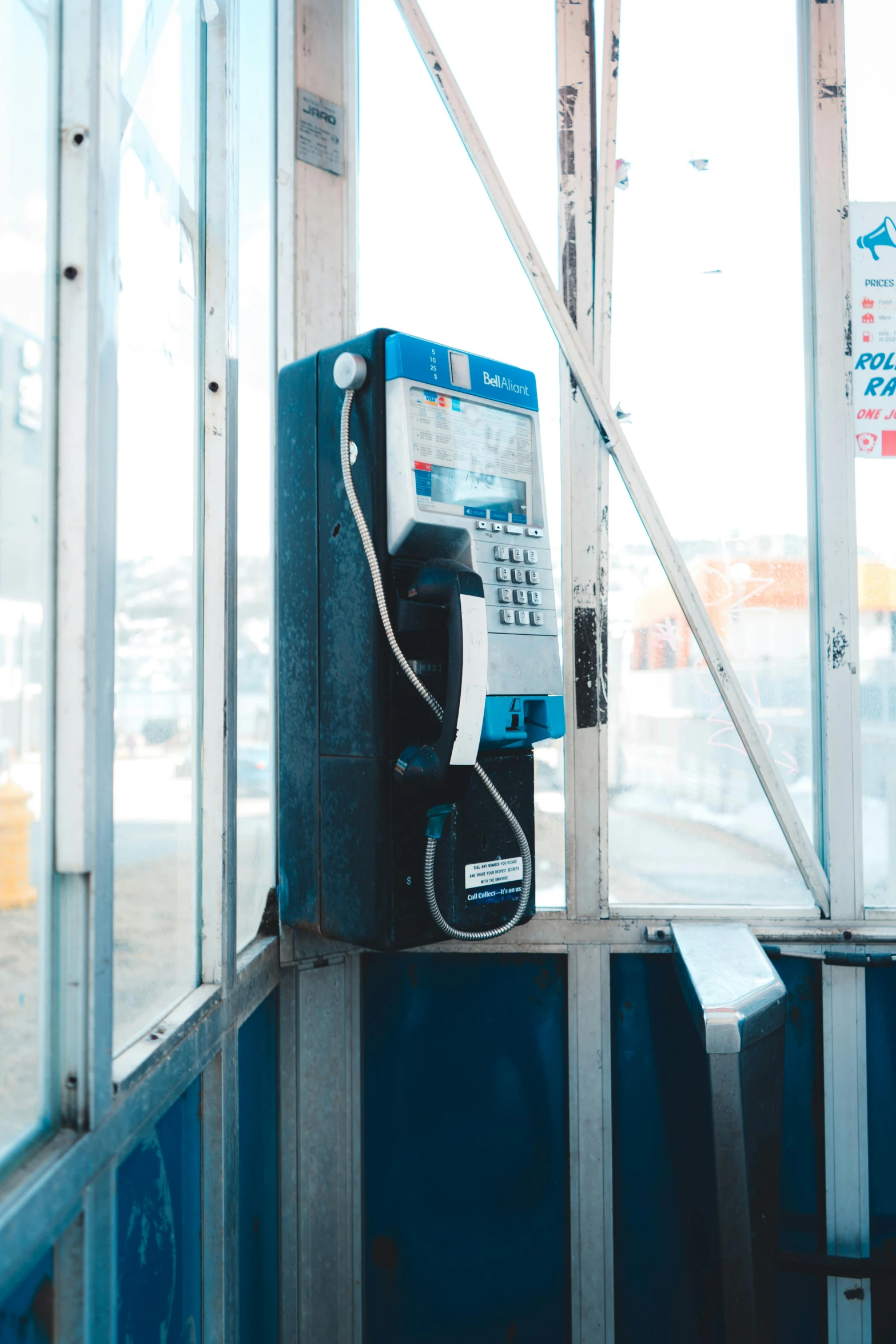 an old payphone sitting next to a window