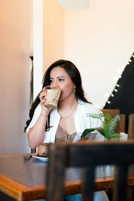 a woman sitting at a wooden table drinking coffee