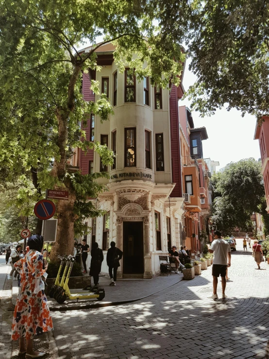 people walking past old city block buildings with an orange statue